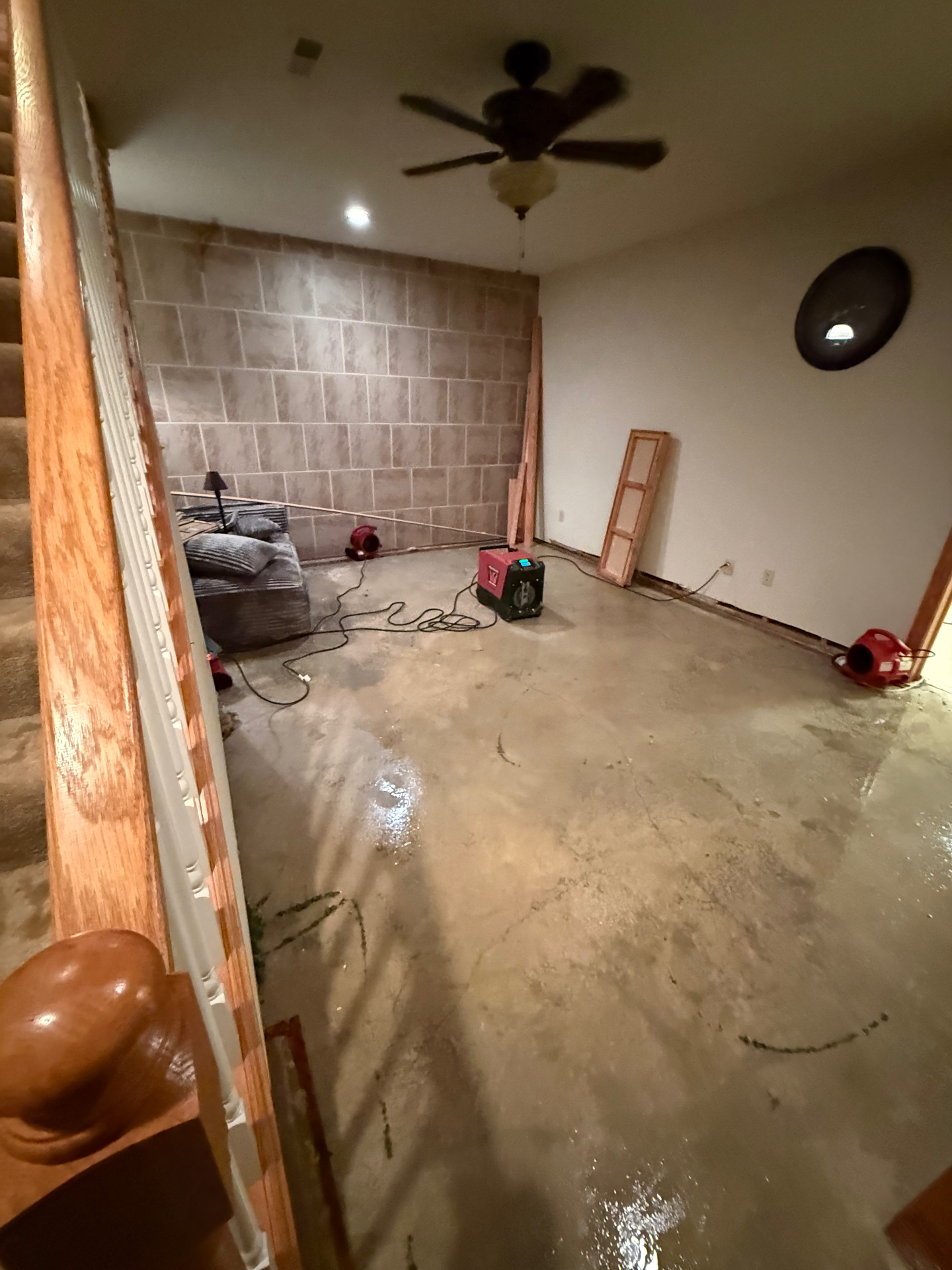 Wet concrete basement floor drying after saturated carpet and pad removal following a hot water tank burst in Central Ohio