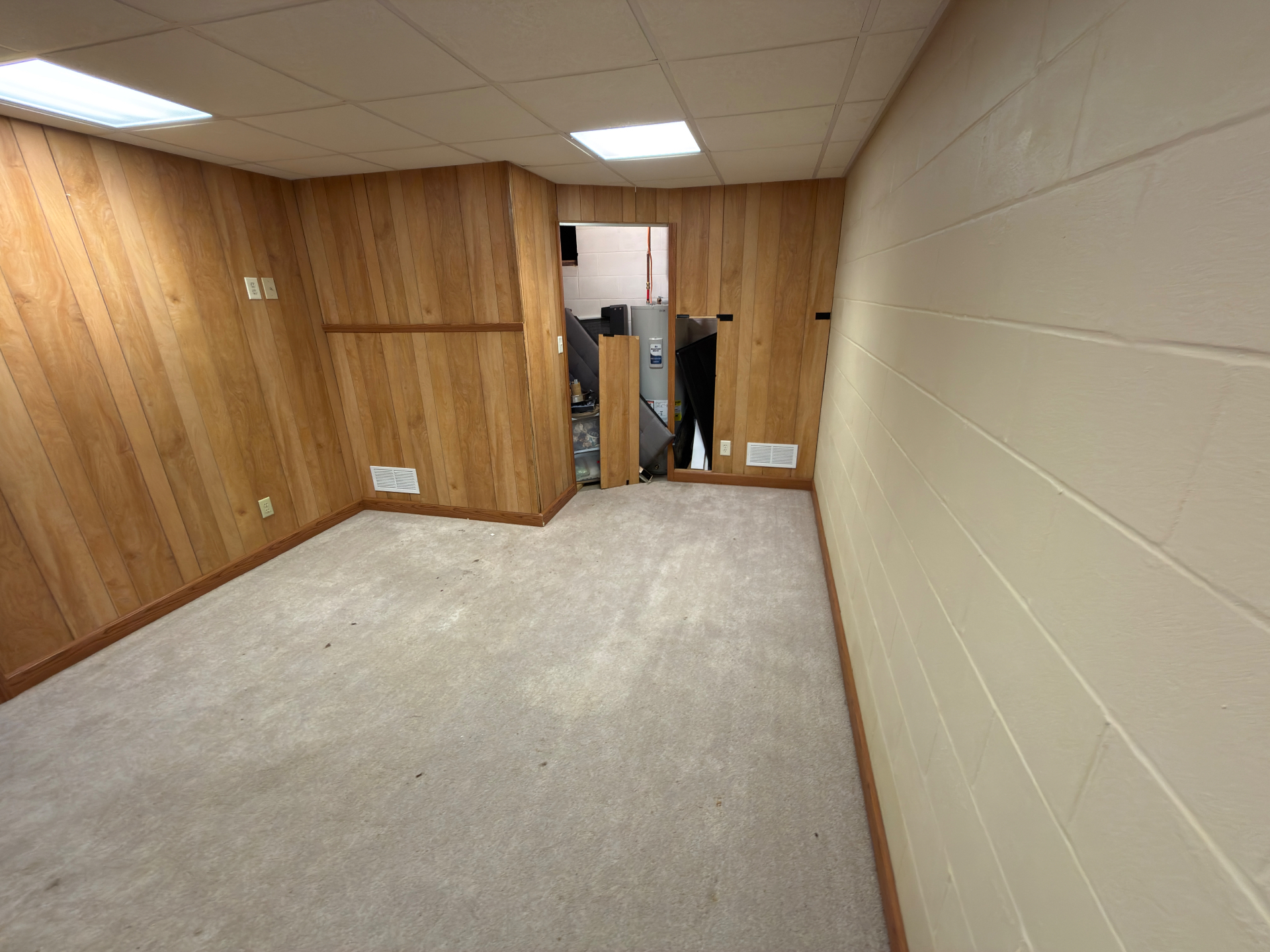 Older carpet in a finished basement before removal after a burst hot water tank in Central Ohio