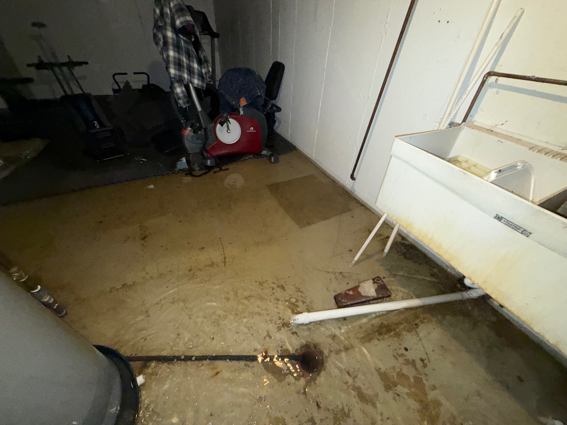 Standing water around a basement floor drain and utility sink following a floor-drain water loss